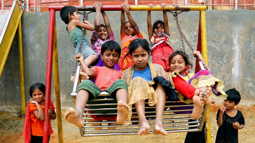 Rohingya refugee children play on a swing at a refugee camp in Cox's Bazar