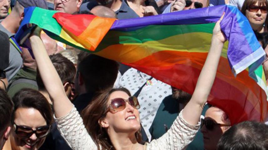 A woman holds up the rainbow flag.