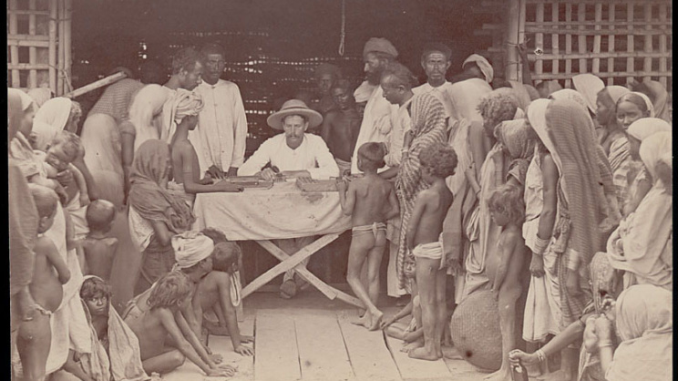 British manager handing out tea tokens to workers; the image reflects the workers’ harsh living conditions. Image source: Wikimedia Commons