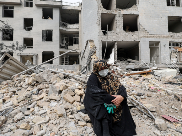 A woman sits outside her destroyed apartment after it was damaged by an airstrike while she was inside, amid the U.S.-Israeli conflict with Iran, in Tehran, Iran, March 12, 2026. Photo: Reuters