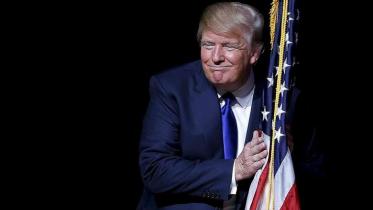 Donald Trump hugging a US flag.jpg
