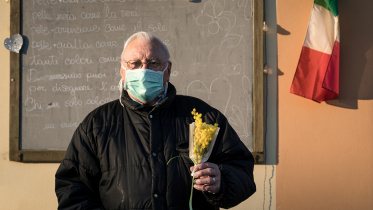 A man wearing a protective mask holds a bouquet of flowers