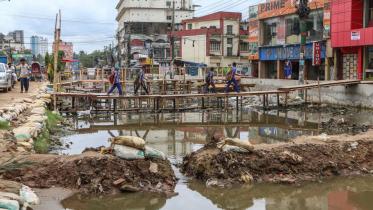 A group of students crosses an inundated portion of a road 