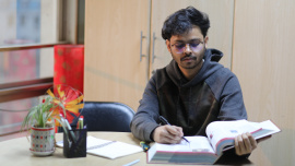 A person sitting with books open, staring intently 