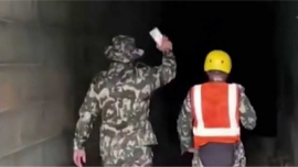 Nepali Army personnel navigate the pitch-black tunnel of the Trishuli Hydroelectric Project using only the faint glow of smartphone flashlights during a search operation for trapped workers. Screengrab/Kathmandu Post