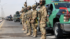 Members of the Iraqi security forces stand next to a convoy moving through the city as they celebrate the withdrawal of US-led coalition forces .jpg