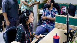 Female employee working diligently while her male counterparts loiter around. 