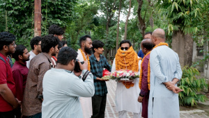 Students gathered around a student leader placing garlands on him.