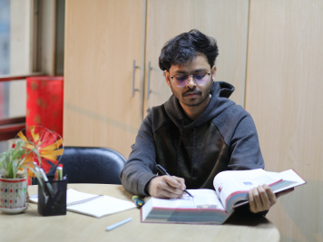 A person sitting with books open, staring intently 