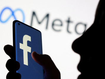 Woman holds smartphone with Facebook logo in front of a displayed logo for Meta in this illustration picture taken October 28, 2021. Photo: Reuters