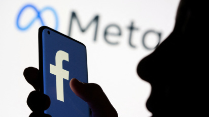 Woman holds smartphone with Facebook logo in front of a displayed logo for Meta in this illustration picture taken October 28, 2021. Photo: Reuters