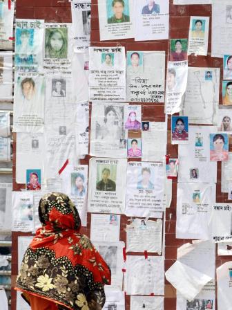 A woman looks at a wall filled with portraits of missing people on May 3, 2013 near the collapsed Rana Plaza building. PHOTO Ashraful Alam Tito Associated Press.jpg